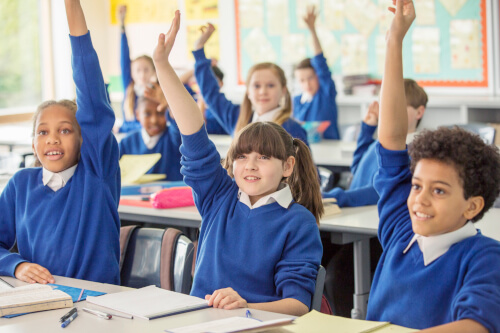 Group of school children with hands up