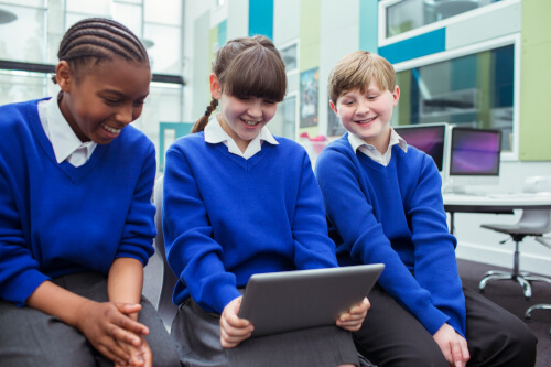 Three UK school children sat at desk