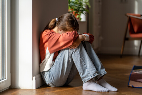 Sad teenager in a room with head in hands