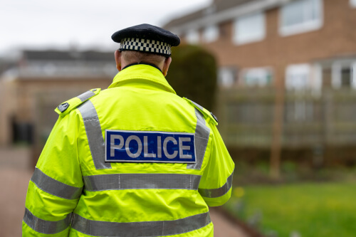 Police officer walking towards a house