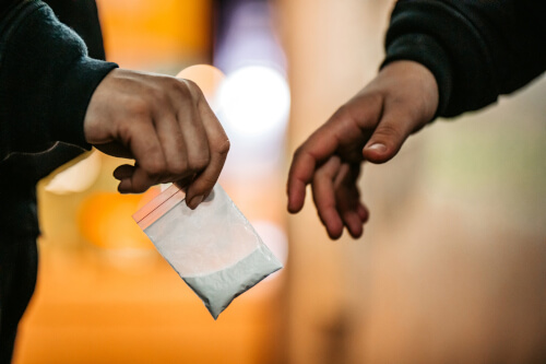 illegal drugs being handed from a dealer to a user