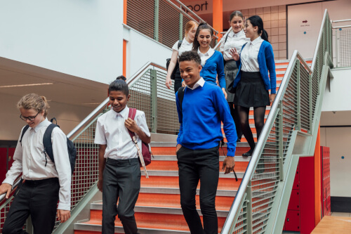 Happy Teenage School Children Walking Down Stairs