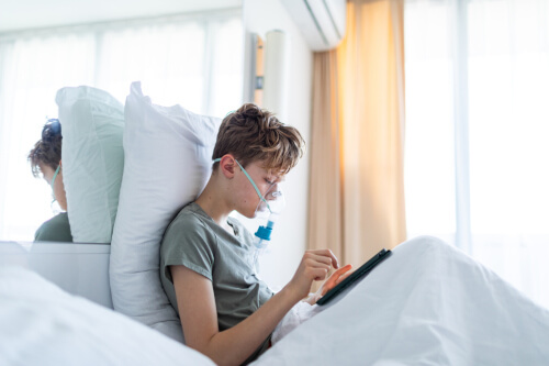 teenager in a hospital bed with ipad