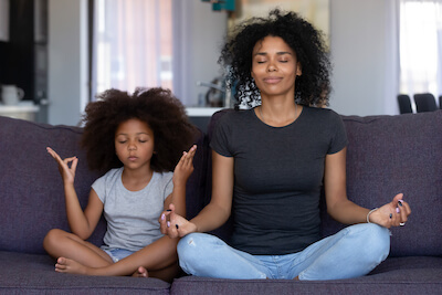 Mother practicing mindfulness exercise for mental health with daughter 