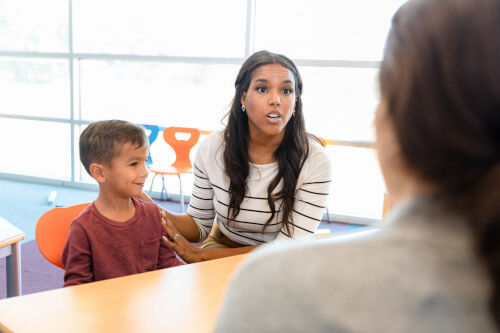 annoyed parent with child speaking to a teacher