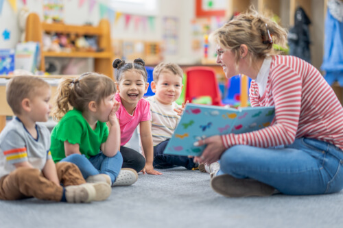 teacher sat down in reading with nursery school children