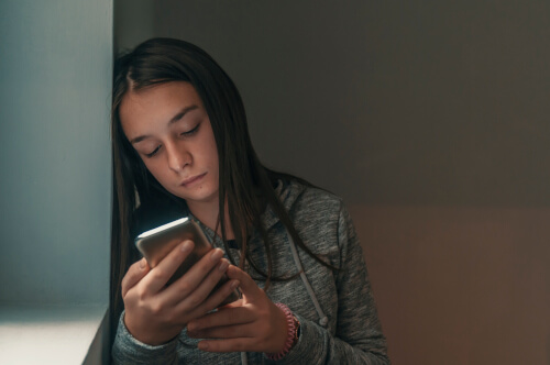 Sad teenage girl with mobile phone
