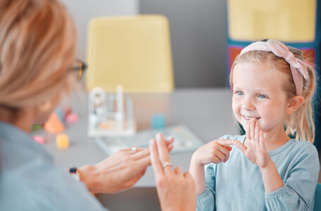 A speech therapist signing with primary school girl